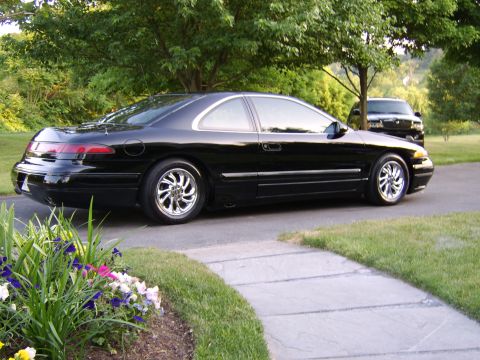 1996 Mercury Grand Marquis - A black coupe is parked on a driveway with a second vehicle in the background.