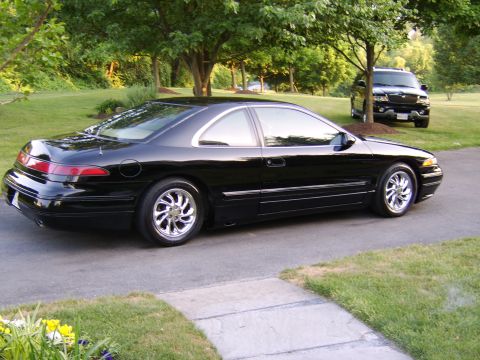 1996 Mercury Grand Marquis - A black coupe with chrome wheels is parked on a driveway, with a black SUV in the background.