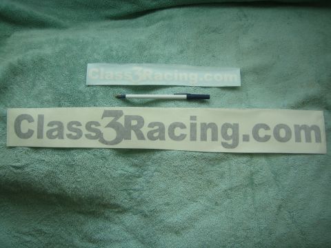 1990 Ford Bronco - Two gray vinyl decals reading 'Class3Racing.com' in different sizes lie on a green towel beside a ballpoint pen for scale.