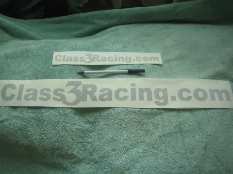 1990 Ford Bronco - larger and a smaller 'Class3Racing.com' gray vinyl decal sit on a green towel with a ballpoint pen for size reference.