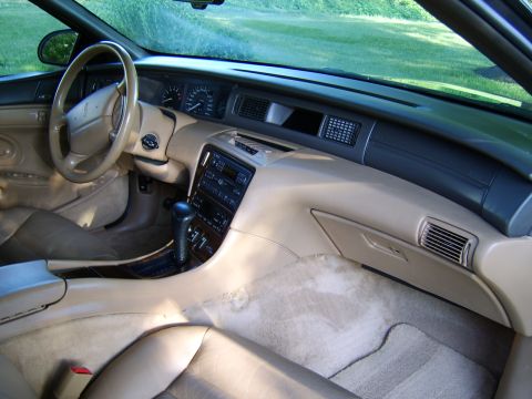 1996 Mercury Grand Marquis - The dashboard and center console of a car, tan upholstery and wood trim accents.