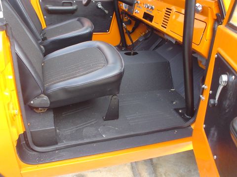 1977 Ford Bronco - The interior of a 1977 Ford Bronco is shown, orange exterior paint and black seats.