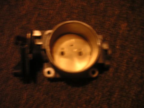 1996 Ford Crown Victoria - A close-up view of a throttle body is shown against a dark, textured background.