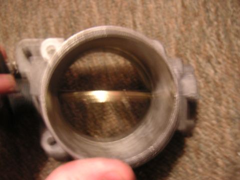 1996 Ford Crown Victoria - A close-up view of a throttle body, showing the butterfly valve inside.