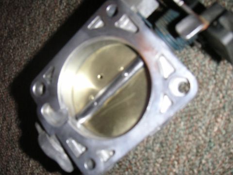 1996 Ford Crown Victoria - A close-up view of a throttle body, a critical engine component, is shown against a textured background.