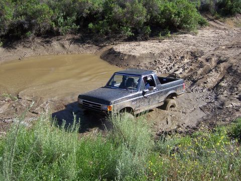 1991 Ford Bronco - This Ford Bronco is deep in the mud, struggling to get through the terrain.