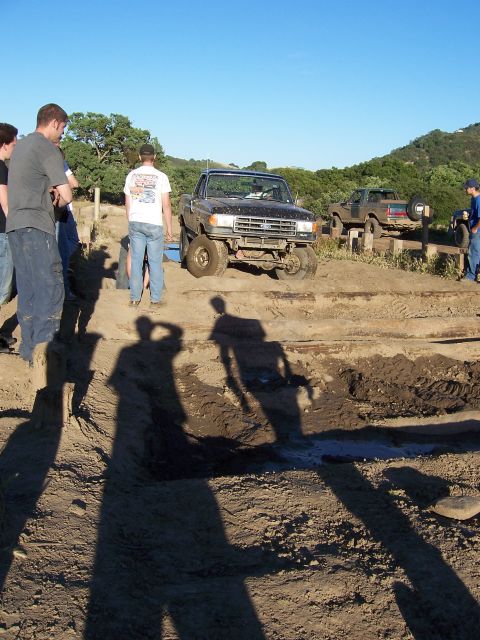 1991 Ford Bronco - A black 1991 Ford Bronco navigates an off-road obstacle while onlookers observe the scene.