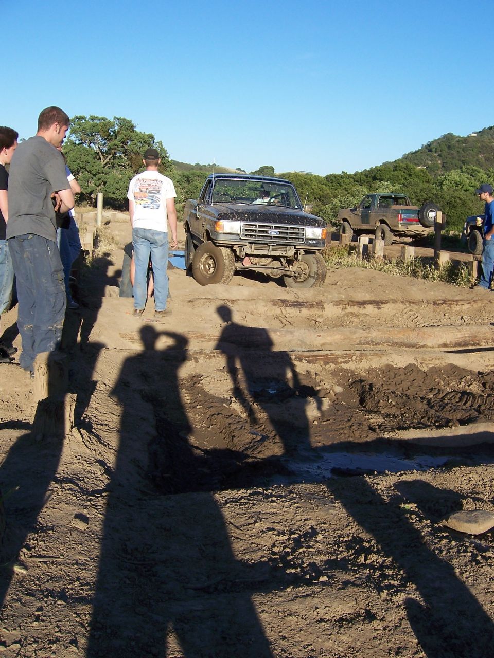 Black 1991 Ford Bronco on an off-road course with people watching