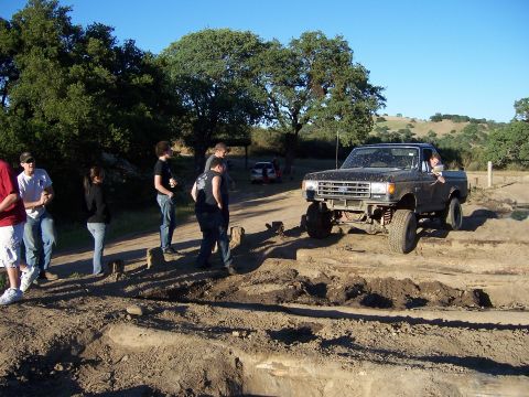 1991 Ford Bronco - Modified Ford pickup truck navigates a challenging dirt obstacle course with onlookers present.
