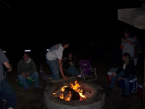 1991 Ford Bronco - Friends enjoy a nighttime bonfire, with several people sitting in chairs and on coolers around the fire pit.