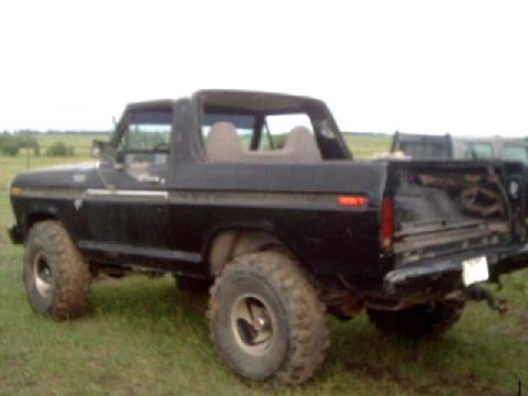 1978 Ford Bronco - This black SUV, possibly a Bronco, is parked outdoors on a grassy field with another vehicle in the background.