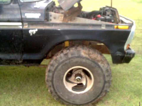 1978 Ford Bronco - Close-up of a vintage Ford truck's front section, revealing its engine and a large off-road tire.