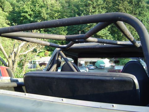 1978 Ford Bronco - View from inside a vehicle, showing a roll cage and rear seats, with other vehicles parked in the driveway.
