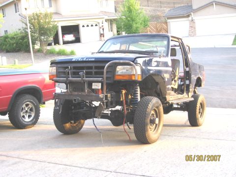 1994 Ford Bronco - A black Ford truck, likely from the early 1990s, is parked in a driveway with its doors removed.