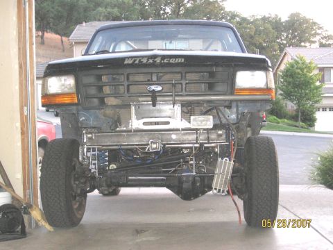 1994 Ford Bronco - Front view of a modified black Ford Bronco, missing its original bumper and grille, revealing mechanical parts.