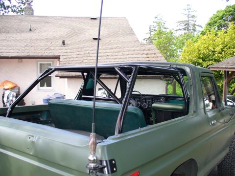 1978 Ford Bronco - The interior of a green Ford Bronco features a custom black roll cage, providing added structural support.