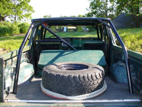 1978 Ford Bronco - Rear view of a 1978 Ford Bronco's interior, showing a roll cage and spare tire.