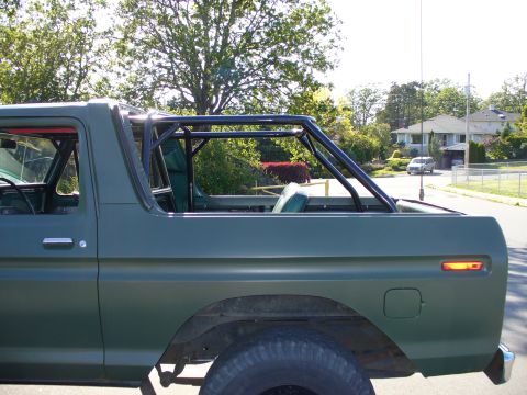 1978 Ford Bronco - Side profile of a green 1978 Ford Bronco an aftermarket roll cage installed in the cabin.
