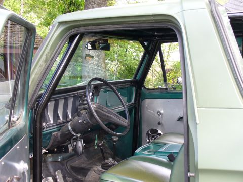 1978 Ford Bronco - The interior of a green 1978 Ford Bronco is visible, complete with a roll cage and dashboard details of course, the dashboard.