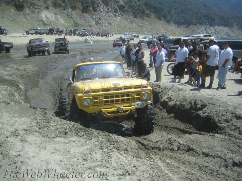 1987 Suzuki Samurai - Modified pickup truck navigates a muddy off-road course with spectators gathered nearby.