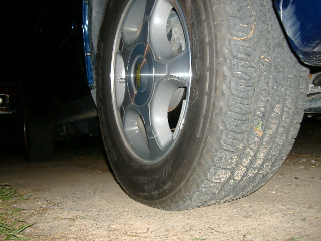 Close-up of a vehicle's wheel and tire on a dirt surface