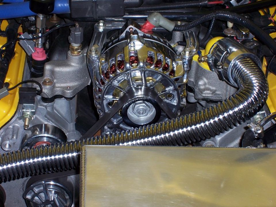 Close-up of a chrome alternator and serpentine belt in an engine