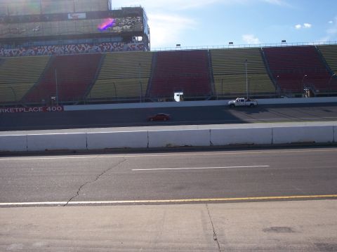 1996 Ford Probe - A race track scene with two vehicles on the asphalt under a bright blue sky.