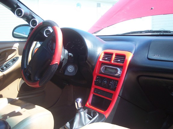 Car interior with red and black steering wheel cover, aftermarket stereo, and red trim around the center console