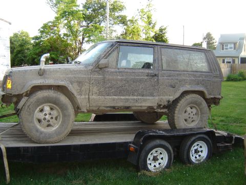 1987 Suzuki Samurai - Mud-caked Jeep Cherokee XJ with a snorkel is loaded onto a trailer.