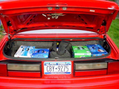 2000 Ford Taurus - The trunk of a red car is open, revealing groceries and a duffel bag inside.