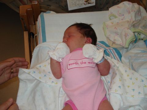 2000 Ford Crown Victoria - A newborn baby rests peacefully in a crib, wearing a pink onesie that reads 'worth the wait'.