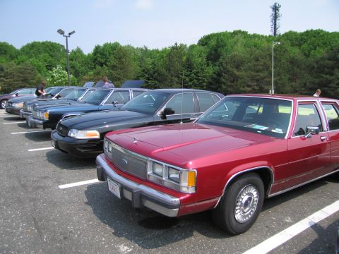 1991 Ford LTD Crown Victoria - Several Ford Crown Victoria LTD sedans are parked in a lot on a sunny day.