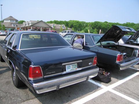 1991 Ford LTD Crown Victoria - Two Ford Crown Victorias are parked side-by-side in a parking lot, one with its trunk open.
