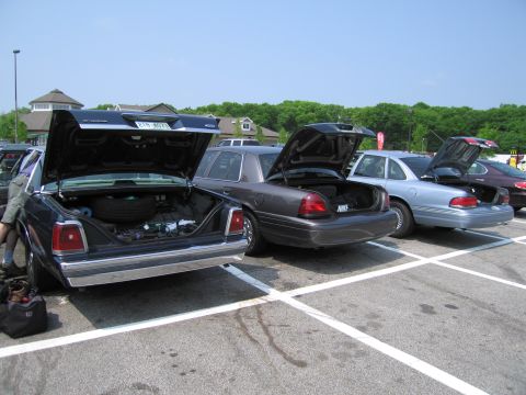 1991 Ford LTD Crown Victoria - Several Ford Crown Victorias are parked in a lot with their trunks open.