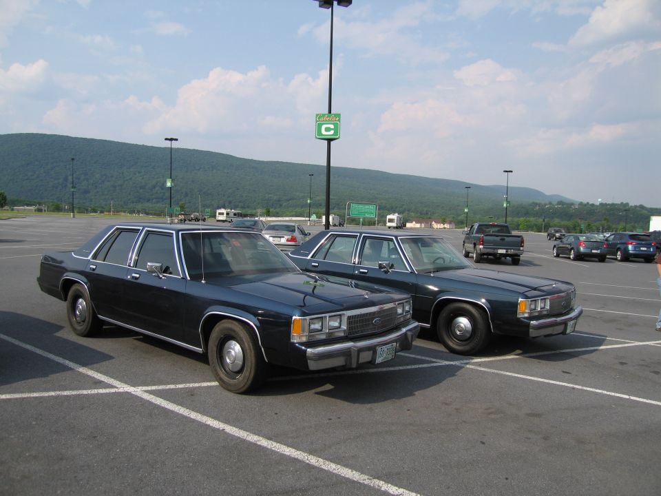Two dark 1991 Ford Crown Victoria LTD sedans parked in a lot