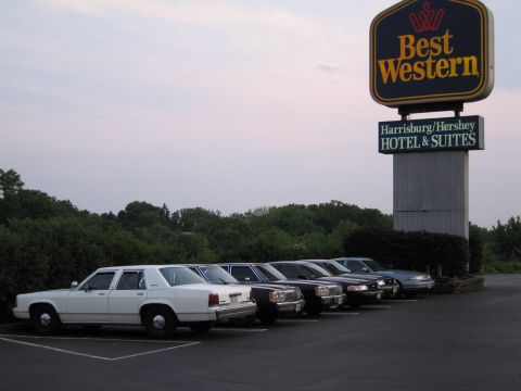 1991 Ford LTD Crown Victoria - A row of sedans, including a white 1991 Ford Crown Victoria LTD, are parked outside a Best Western hotel.