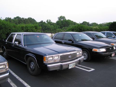 1991 Ford LTD Crown Victoria - A dark blue 1991 Ford Crown Victoria LTD is parked in a lot alongside other vehicles.