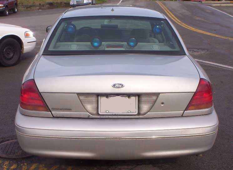 Rear view of silver 2002 Ford Crown Victoria with blue lights in the back window