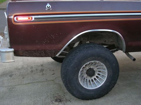 1978 Ford F-250 - The rear side of a brown 1973 Ford F-250 pickup truck is shown with a large tire and chrome trim.