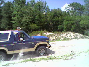 1986 Ford Bronco - This 1986 Ford Bronco is kicking up dust as it drives on a sandy path.
