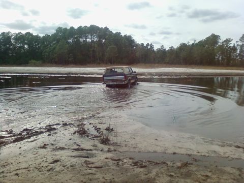 1986 Ford Bronco - Ford Bronco navigates shallow water, kicking up ripples.