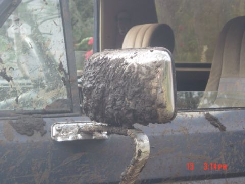 1986 Ford Bronco - Mud covers the side mirror and door of a 1986 Ford Bronco, indicating off-road use.
