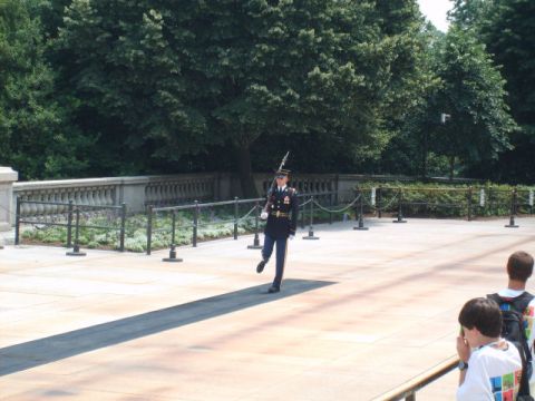 2004 Ford Crown Victoria - A soldier stands guard at a memorial site, with visitors in the foreground.