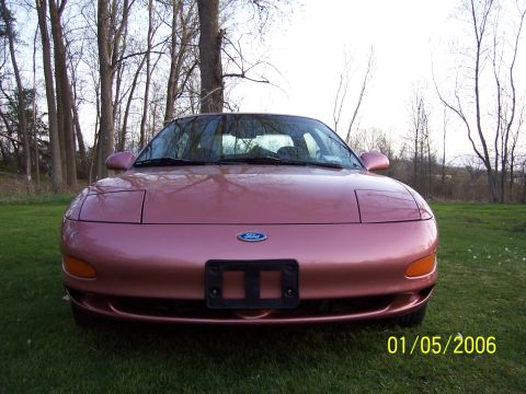1996 Ford Probe - A pink Ford Probe is shown from the front, parked outdoors on a grassy area with trees.