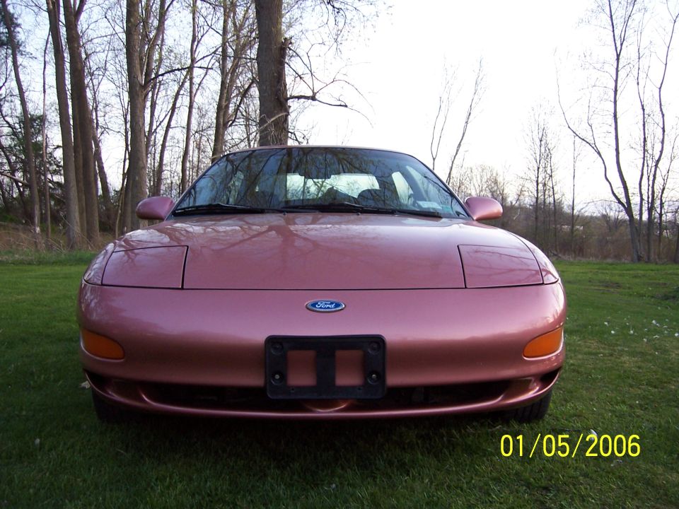 Pink Ford Probe front view, parked on grass with trees in background