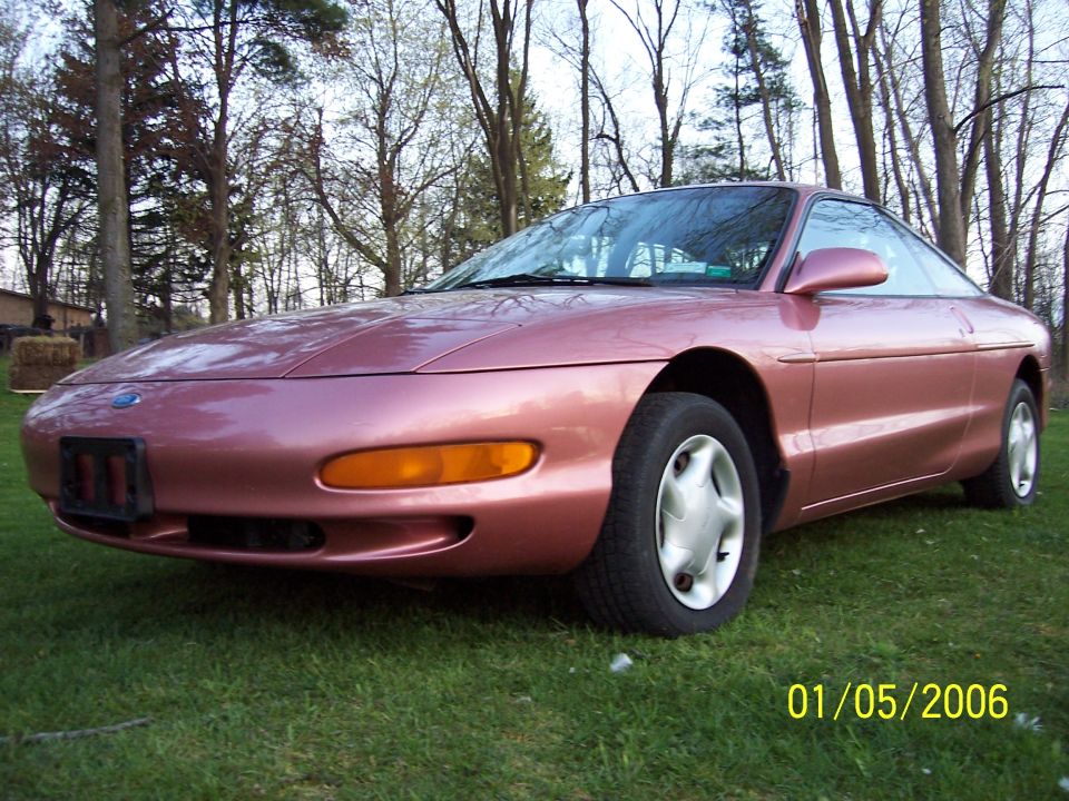 Pink coupe parked on grass, front 3/4 view. Date stamp 01/05/2006