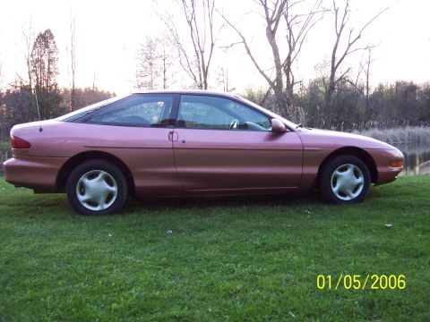 1996 Ford Probe - Side profile of a pink 1996 Ford Probe coupe on a grassy area.