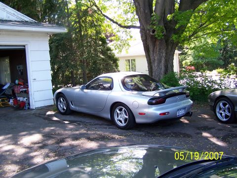 1996 Ford Probe - Silver Mazda RX-7 parked in a driveway on a sunny day.