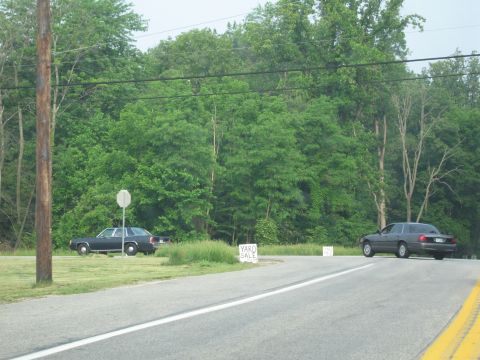 1991 Ford LTD Crown Victoria - Two dark sedans are visible on a road with a yard sale sign in the background.