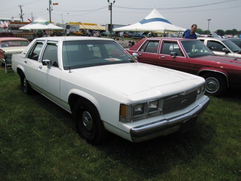 1991 Ford LTD Crown Victoria - A white 1991 Ford Crown Victoria LTD is parked on grass at an outdoor event.